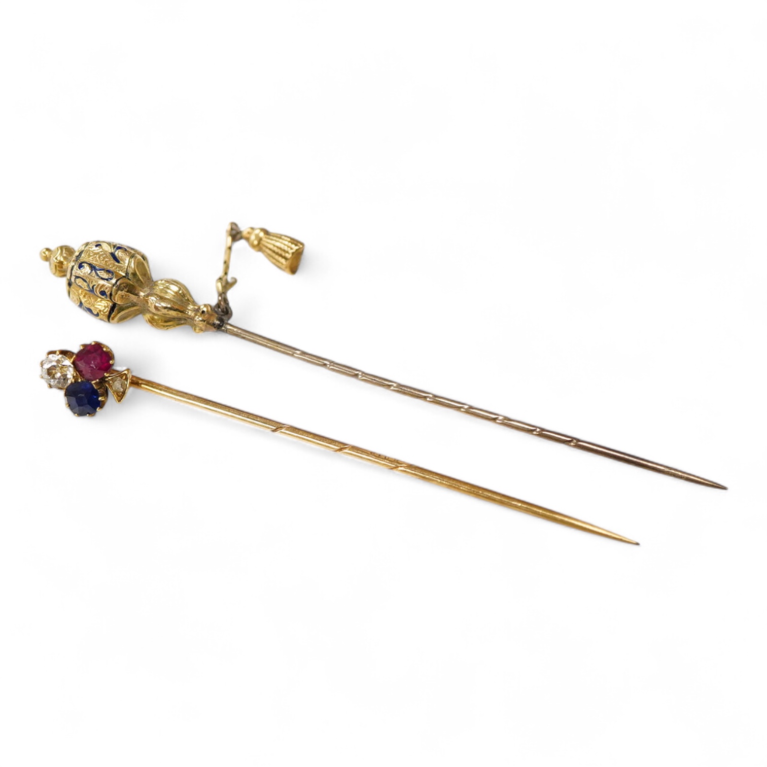 An early 20th century Viennese yellow metal, ruby, diamond and sapphire set 'clover' stick pin, 68mm, together with a yellow metal and blue enamel set stick pin.